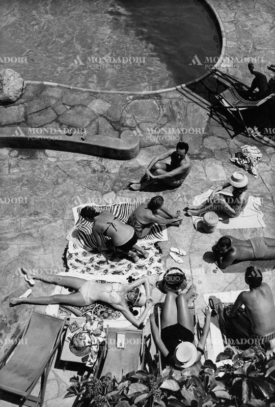 Bathers wearing their bathing suit at the poolside of the bathing establishment La canzone del mare, the smartest hangout in Marina Piccola bay. Capri (Naples), Italy, July 1960. SPECIAL FEE  - CONTACT US FOR NOT EDITORIAL USAGE