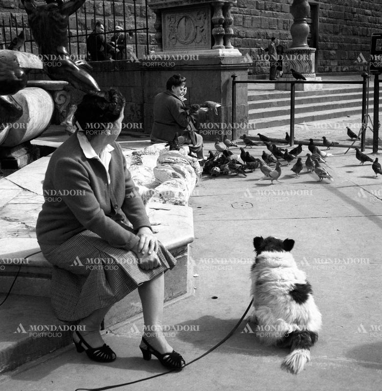 A woman with a dog sitting by the Fountain of Neptune in Piazza della Signoria. Florence, 1950s SPECIAL FEE  - CONTACT US FOR NOT EDITORIAL USAGE