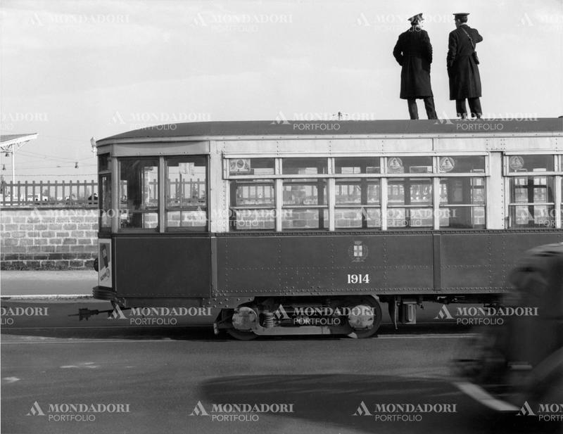 Tram drivers standing on a tram to see inside the San Siro racecourse. This picture is taken from the monography "Mario De Biasi. Il mio sogno è qui", curated by Enrica Viganò, published in 2016 by Mondadori Electa. Milan (Italy), 1950 SPECIAL FEE - CONTACT US FOR EVERY USAGE