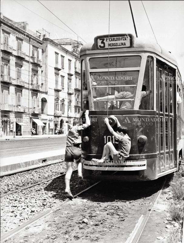 Two boys jumping sneakily on a tram. This picture is taken from the monography "Mario De Biasi. Il mio sogno è qui", curated by Enrica Viganò, published in 2016 by Mondadori Electa. Naples, 1954 SPECIAL FEE - CONTACT US FOR NOT EDITORIAL USAGE