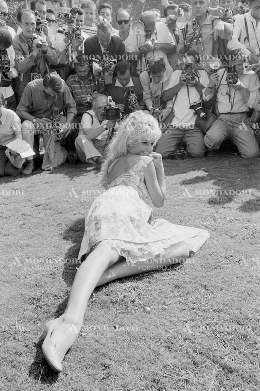 French actress Brigitte Bardot sitting on the grass and being photographed by the journalists at the 19th Venice International Film Festival. Venice, August 1958 SPECIAL FEE  - CONTACT US FOR NOT EDITORIAL USAGE