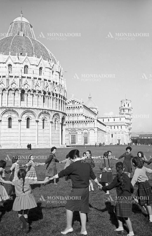 A group of women and little girls playing the ring-around-the-rosy in piazza del Duomo. Pisa, 1963 SPECIAL FEE  - CONTACT US FOR NOT EDITORIAL USAGE