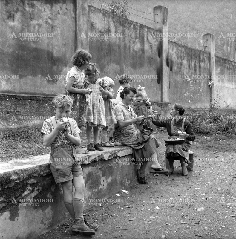 A woman giving some fruits to some children. Bolzano, December 1954 SPECIAL FEE  - CONTACT US FOR NOT EDITORIAL USAGE