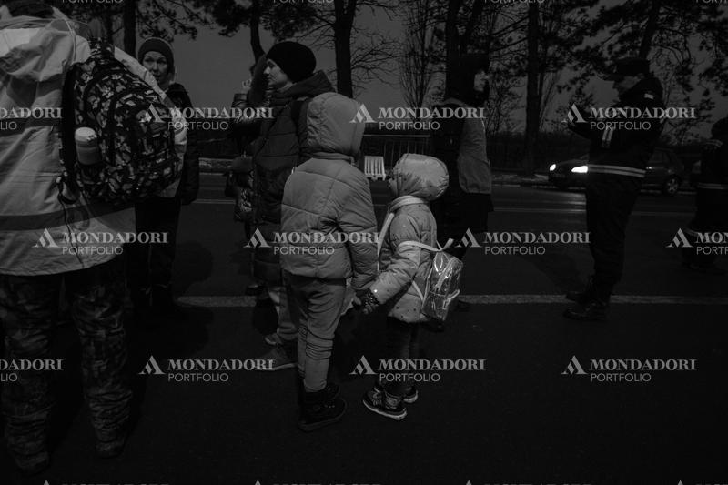 Two children shake hands on the street as they wait for directions on where to go. Siret (Romania), March 8th, 2022
