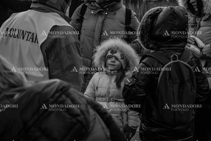 A Ukrainian girl watches a volunteer from the Siret refugee reception center. Siret (Romania), March 8th, 2022