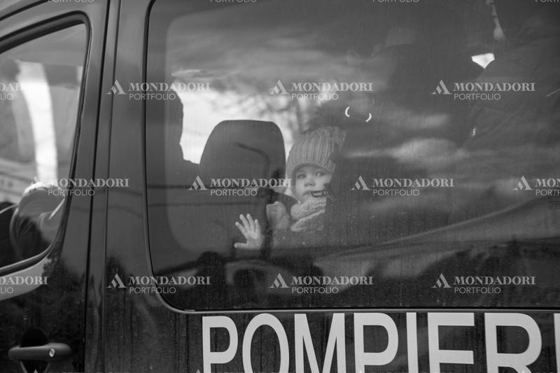A Ukrainian child looks through the glass of the fire bus. Siret (Romania), March 8th, 2022