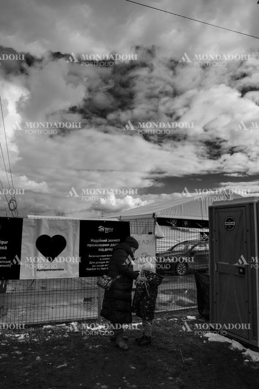A mother helps her daughter fasten her jacket. Siret (Romania), March 8th, 2022